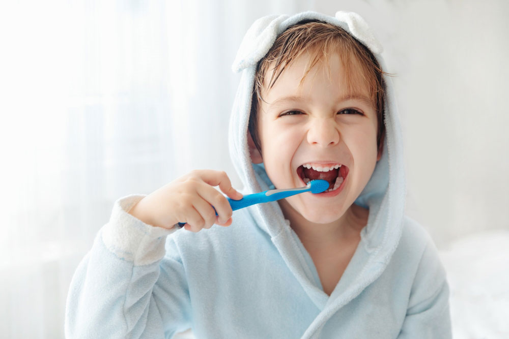 Smiling little boy brushing teeth