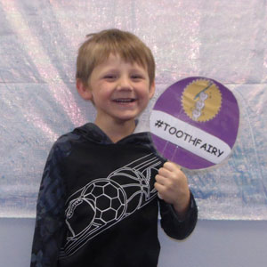 little boy holding dental banner and smiling